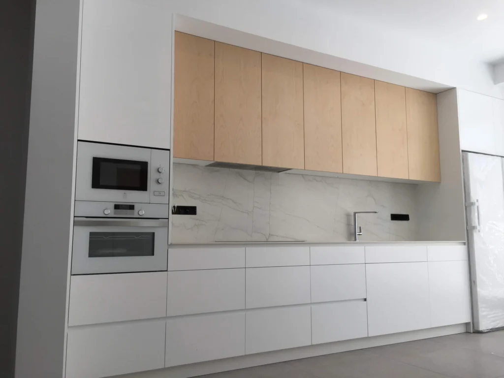 Cocina blanca con frentes superiores en acabado roble
